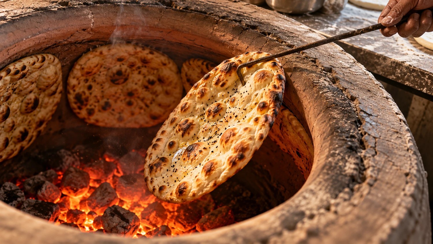 Out of the tandoor — Bread goes onto the clay wall and comes off about ninety seconds later.